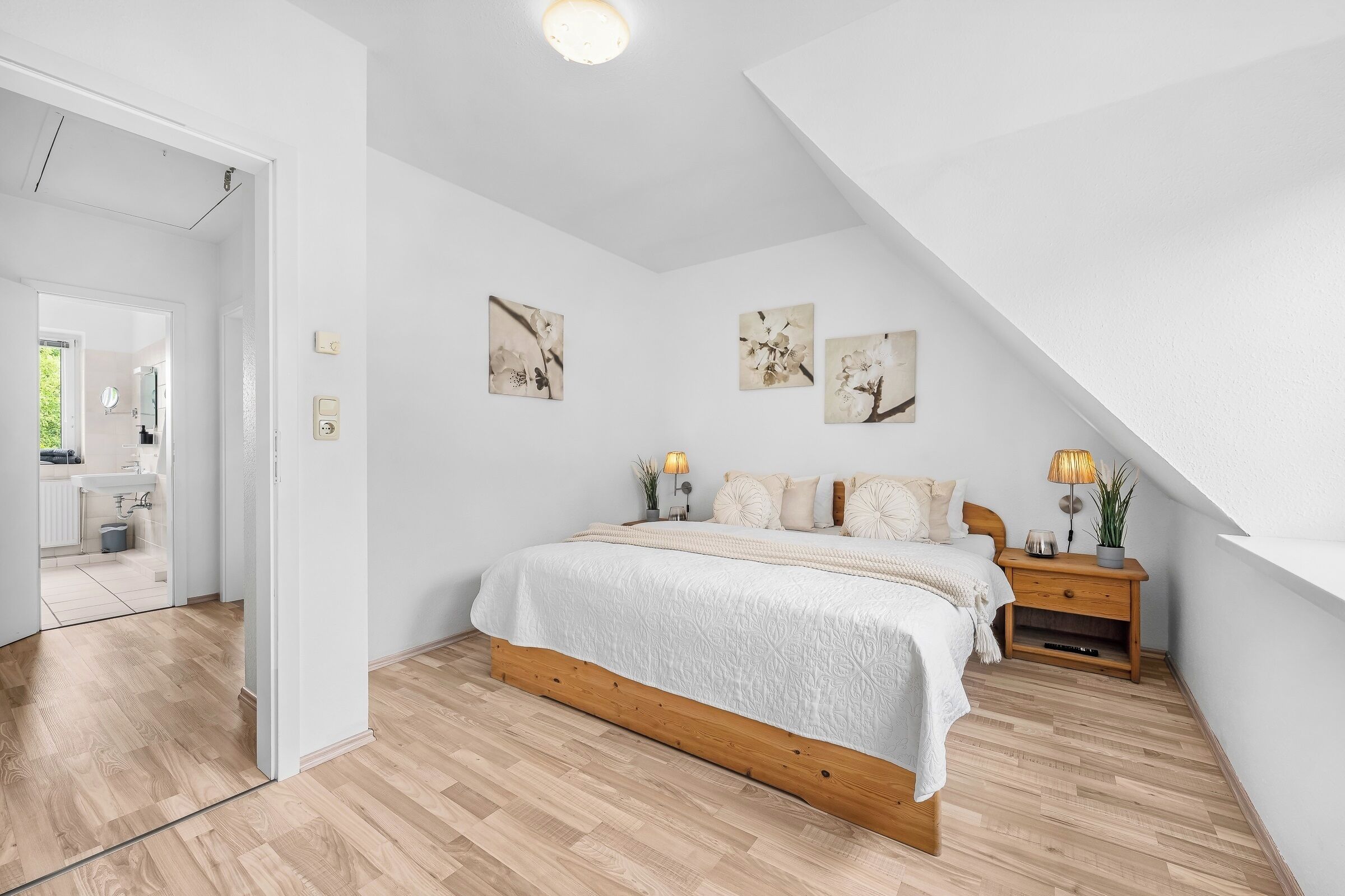 A bedroom with a wooden bed, white walls, and a sloped ceiling.