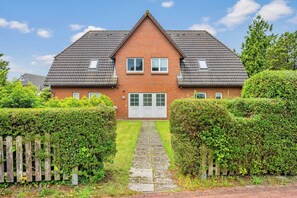 Ein zweigeschossiges Haus mit symmetrischer Fassade, einem mittleren Eingang und einem kleinen Vorgarten.