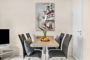 A dining area with a table, chairs, a fruit bowl, and a painting on the wall. - Enjoy a relaxing getaway at the "Küstenzeit SPO" vacation apartment. (Sankt Peter-Ording)