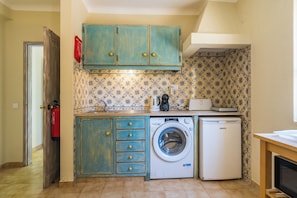 A compact kitchen with a washing machine, a small refrigerator, and a microwave. - SEAS THE DAY (Luz)