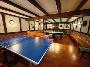 A billiards room with a pool table, a billiard table, and a seating area with benches. - SEAS THE DAY (Luz)
