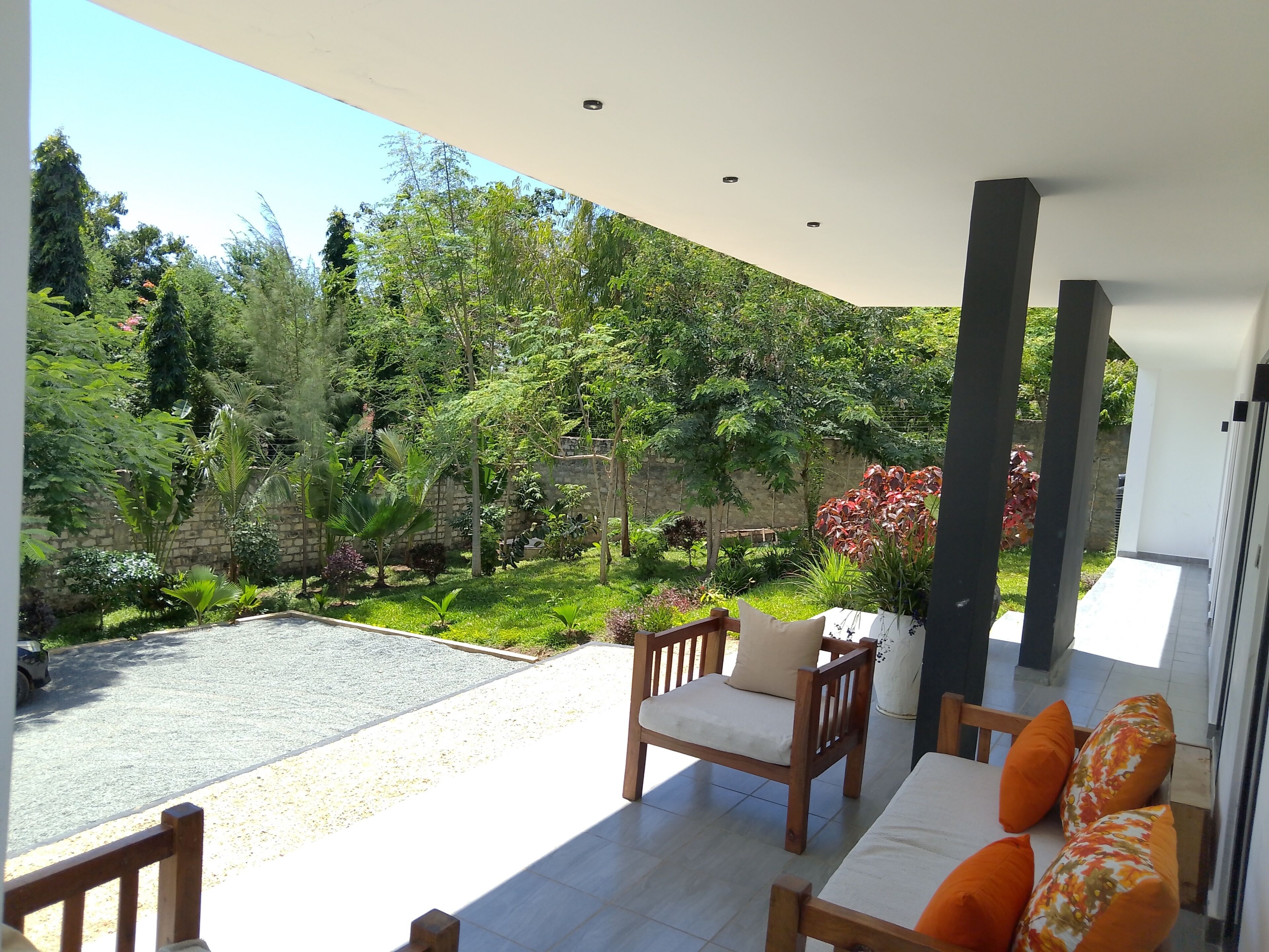 Un espace extérieur aménagé, abrité et doté de sièges, offrant une vue sur un jardin paysager.