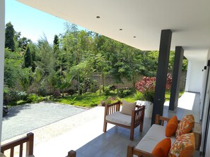A covered outdoor seating area with a view of a landscaped garden. - PES VILLA DIANI (Diani)