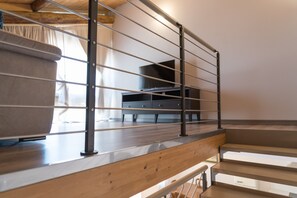 A wooden staircase with metal railings, a flat-screen TV, and a sofa in a modern interior.