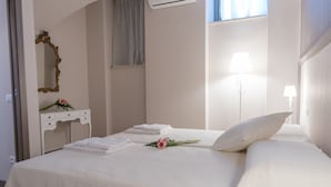 Quarto de hotel com uma cama, toucador com espelho e janela com cortinas.
