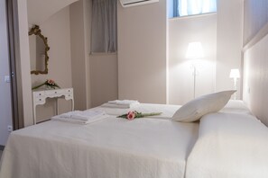 Una habitación de hotel con una cama, una tocador con espejo y un ventanal con cortinas.