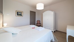Un dormitorio con cama, armario, una silla y un cuadro en la pared.