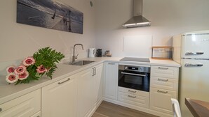 Una cocina moderna con armarios blancos, una campana extractora de acero inoxidable, un horno empotrado y un lavamanos.