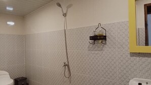 Casa de banho com chuveiro, sanita e lavatório.