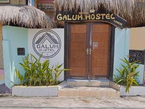 A hostel entrance with a wooden door and a sign that reads 'GALUH HOSTEL.' - Galuh Hostel Lombok (Pemenang)