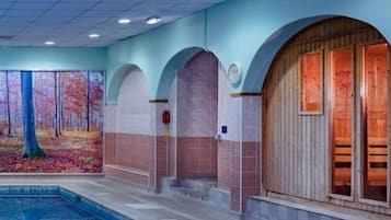 An indoor swimming pool area with a mural, arched niches, and a wooden door.