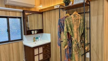 Un baño con tocador de madera, espejo, perchero para batas y ventana.