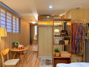 Quarto compacto com área de refeições, armário e cama.