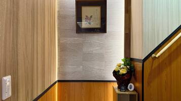 A wooden staircase with a framed picture on the wall, a small shelf with a vase of flowers, and a light switch on the wall.
