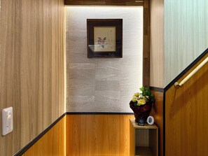 A wooden staircase with a framed picture on the wall, a small shelf with a vase of flowers, and a light switch on the wall. - TOKYO STAR HOUSE (Tokyo)