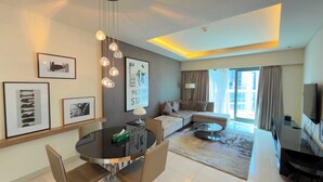 A modern living room with a sofa, a dining table with chairs, a TV, and artwork on the walls.
