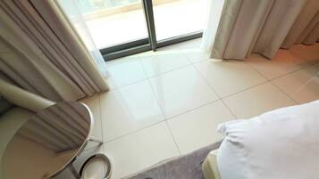 A hotel room with a large sliding glass door, a round table, and a bed.