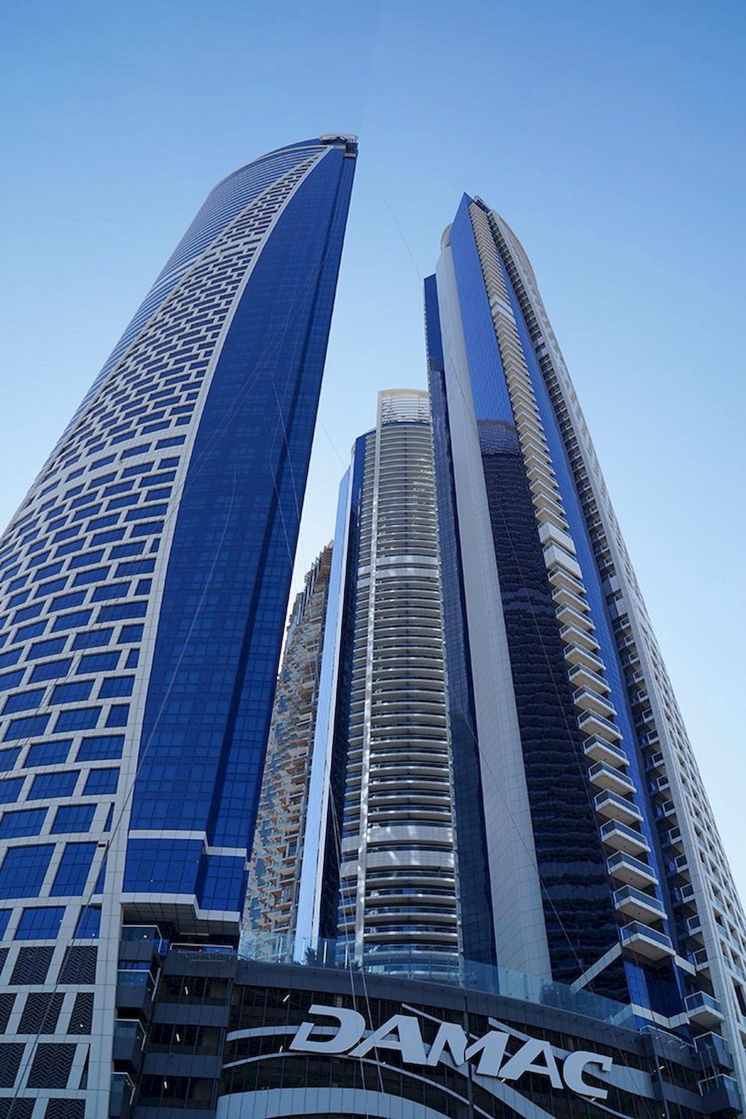 Un immeuble de grande hauteur, dont la base est ornée du logo bien visible de DAMAC.