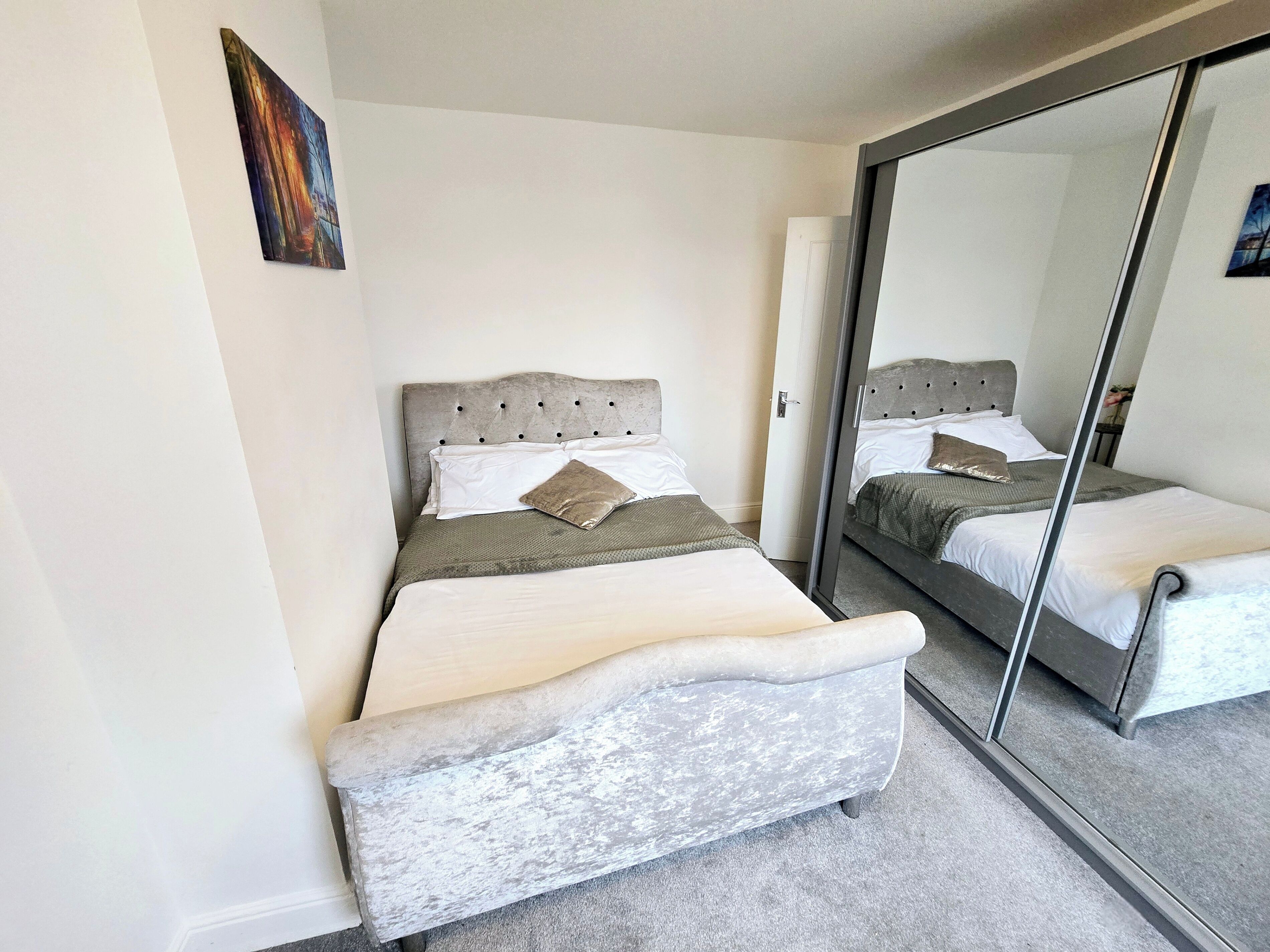 A bedroom with a bed, a mirror, and a door.