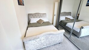 Un dormitorio con cama, espejo y puerta.