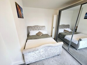 A bedroom with a bed, a mirror, and a door. - Spacious Home, Parking (Dartford)