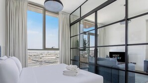 Hotellihuone, jossa on suuri sänky, sohva ja näkymä kaupungin ylle.
