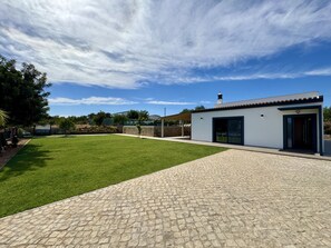 A modern building with a paved driveway, a well-maintained lawn, and a clear sky. - ALGARVE COUNTRY MODERN VILLA WITH POOL by HOMING (Faro)