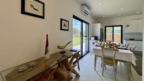 Een eetruimte met een glazen tafel, stoelen en uitzicht op de omgeving.