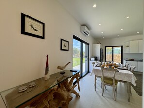 A dining area with a glass table, chairs, and a view of the outdoors. - ALGARVE COUNTRY MODERN VILLA WITH POOL by HOMING (Faro)