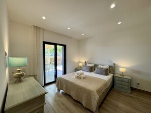 A bedroom with a bed, bedside tables, a lamp, and a sliding glass door leading to an outdoor area. - ALGARVE COUNTRY MODERN VILLA WITH POOL by HOMING (Faro)