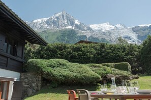 A mountain lodge with a dining area overlooking snow-capped peaks. - Géroux- Modern Apt | Quiet | Mountain View | Garden (Chamonix-Mont-Blanc)