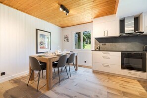 A modern kitchen with wooden flooring, white cabinetry, and a built-in oven. - Géroux- Modern Apt | Quiet | Mountain View | Garden (Chamonix-Mont-Blanc)