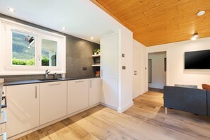 Eine moderne Küche mit weißen Schränken, einer dunklen Arbeitsplatte und einer Holzbalkendecke.