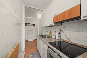 Et køkken med hvide skabe, en granitbordplade, en indbygget ovn og et træskab.
