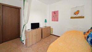 Ein Schlafzimmer mit einem Bett, einem Fernseher auf einer Holzkabine, einer Tür und einem Bild an der Wand.