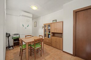 Una cocina compacta con una mesa de comedor, sillas, un armario de madera y una lámpara en el techo.