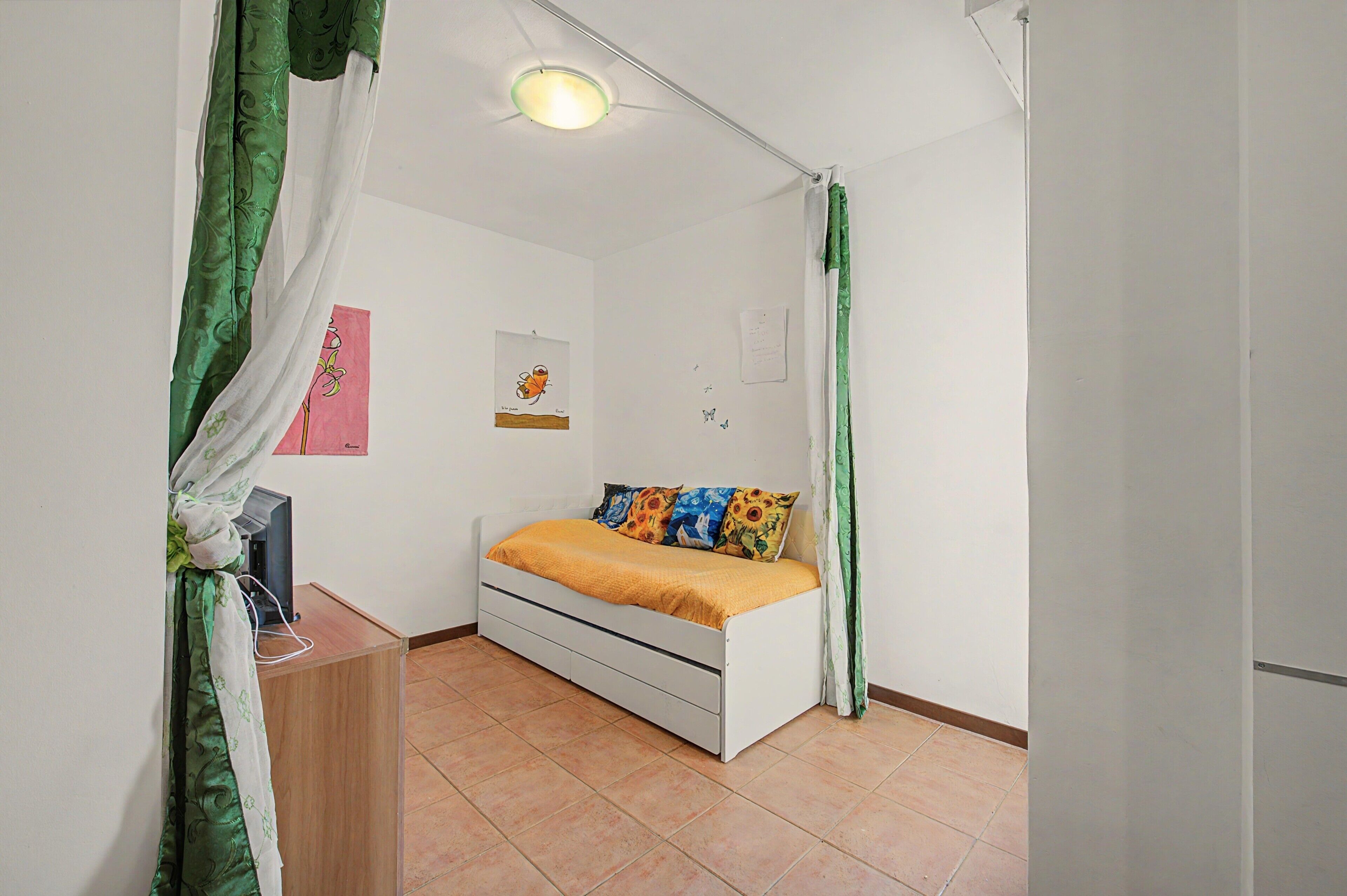 Une chambre à coucher avec un lit, un bureau et une étagère fixée au mur.