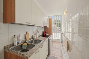 A kitchen with white cabinets, a granite countertop, a stainless steel sink, and a view of the outside. - "Casa Ai Piani" - balcony with Grigna view, Wi-Fi, AC and parking near Piani Resinelli (Piano dei Resinelli)