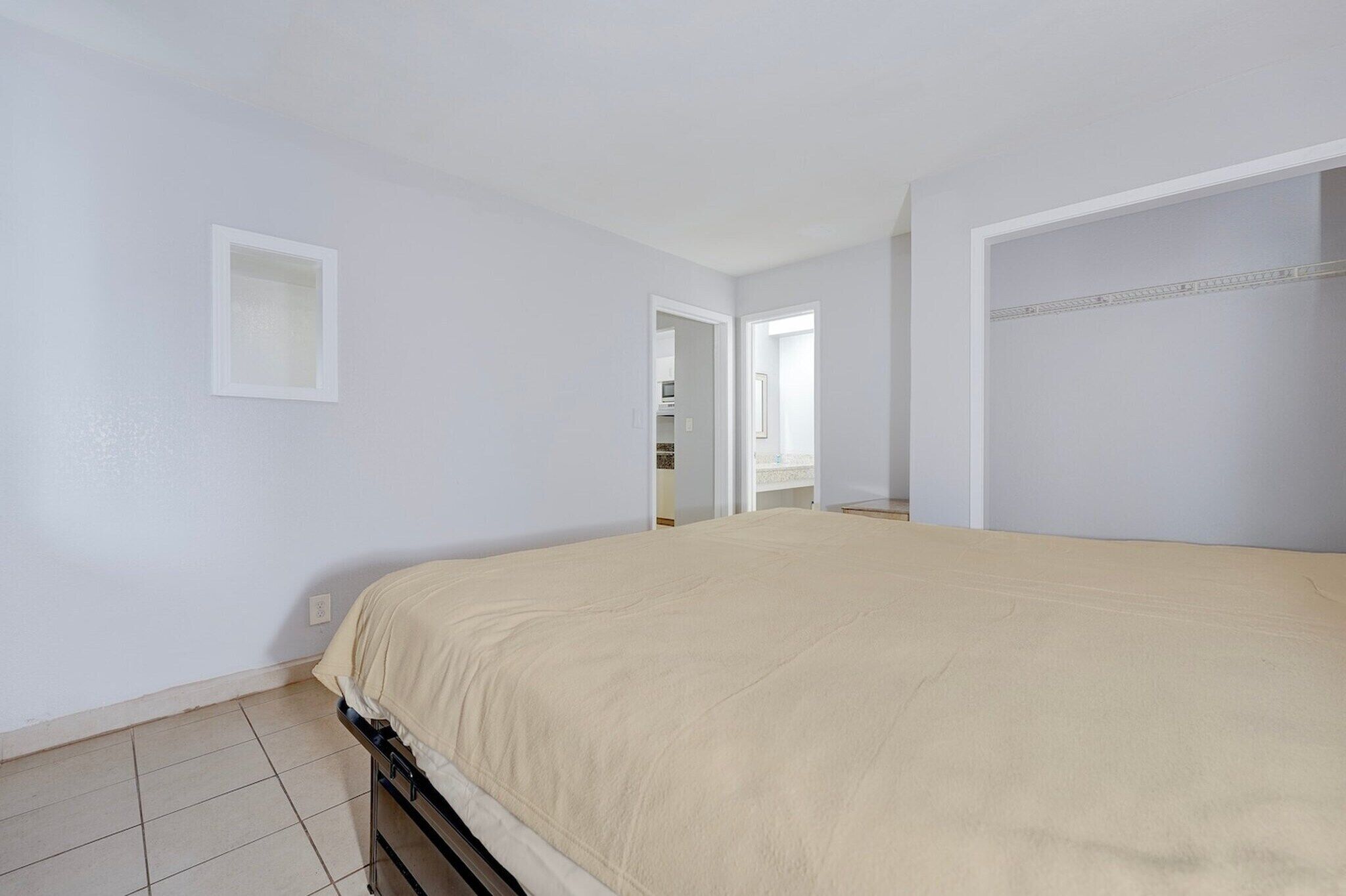 A bedroom with a bed, a door leading to a bathroom, and a small window.
