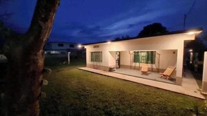Una casa moderna con un porche cubierto, dos ventanas y un jardín.