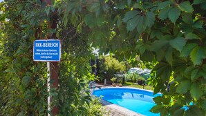 Una piscina rodeada de exuberante vegetación, con un cartel que indica zona privada.
