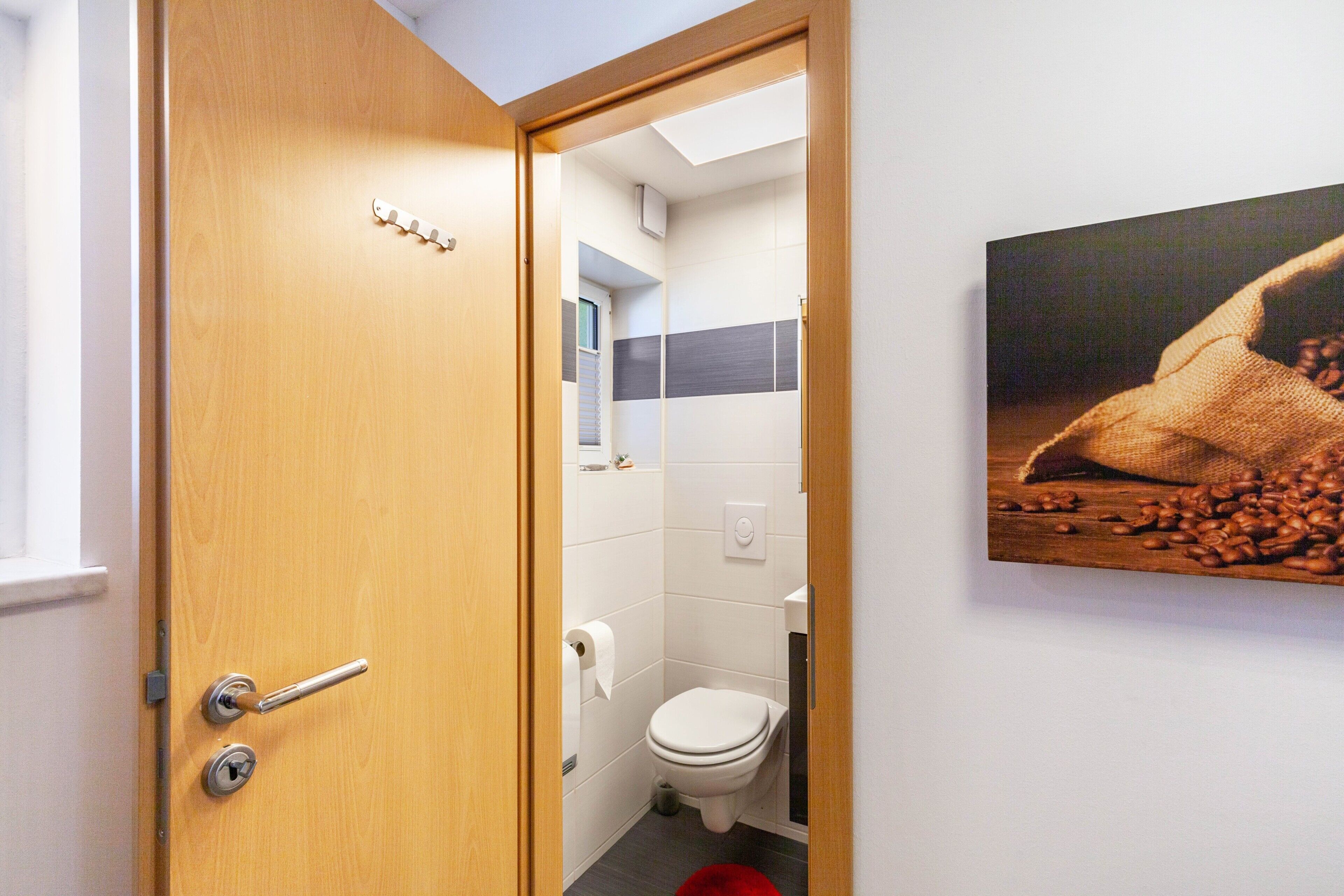 A bathroom with a toilet, a roll of toilet paper, and a wooden door.