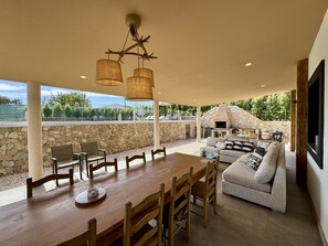 A covered outdoor dining area with a stone wall, a stone oven, and a view of the landscape. - Algarve Country Modern Villa by Homing (Faro)