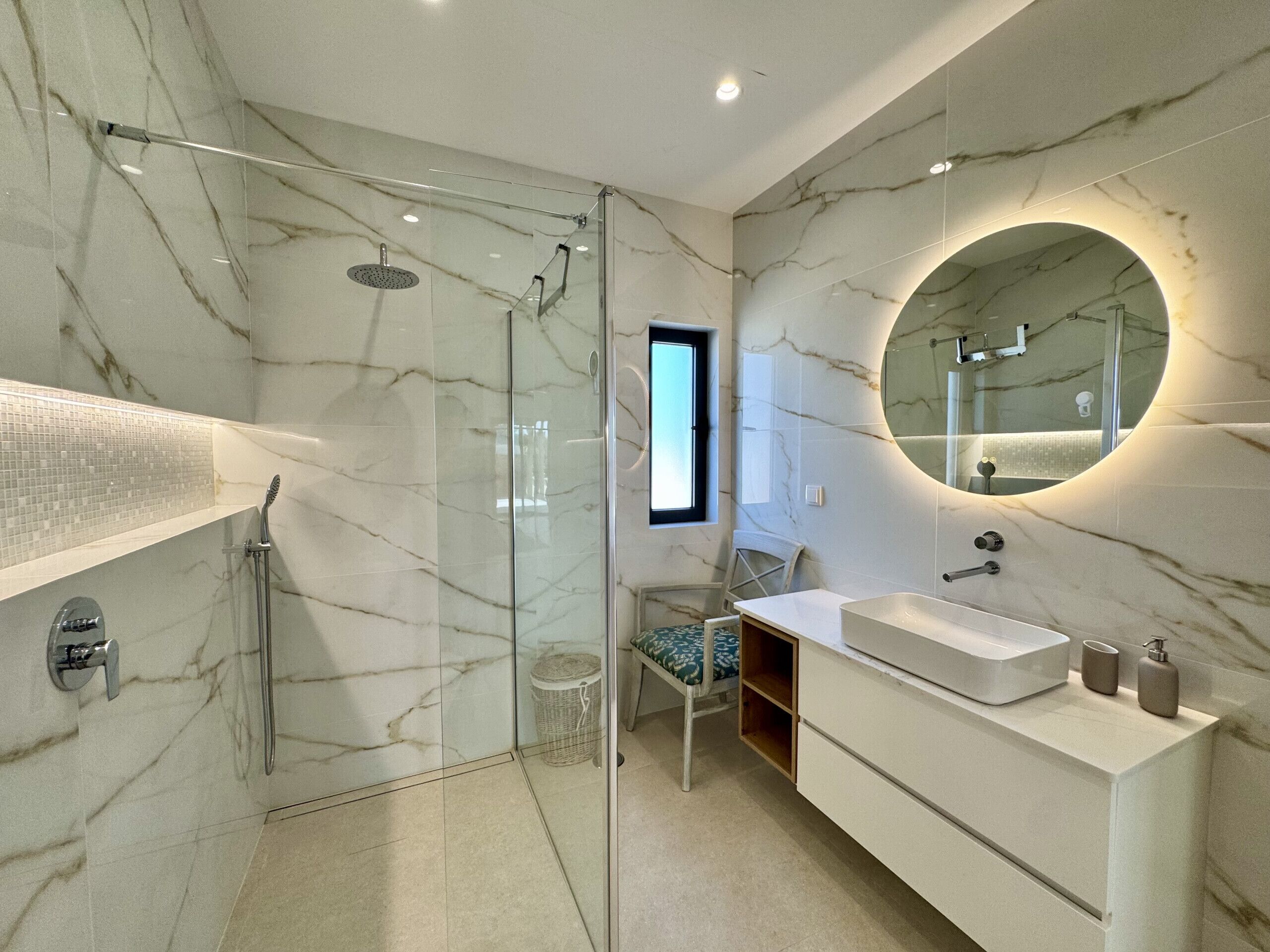 Un baño moderno con ducha de vidrio, un espejo grande y un tocador blanco.