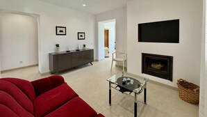 En moderne stue med en rød sofa, et glasbord, en pejs og et minimalistisk design.