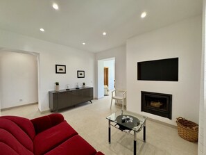 Ein modernes Wohnzimmer mit einem roten Sofa, einem Glastisch, einem Kamin und einem minimalistischen Design.