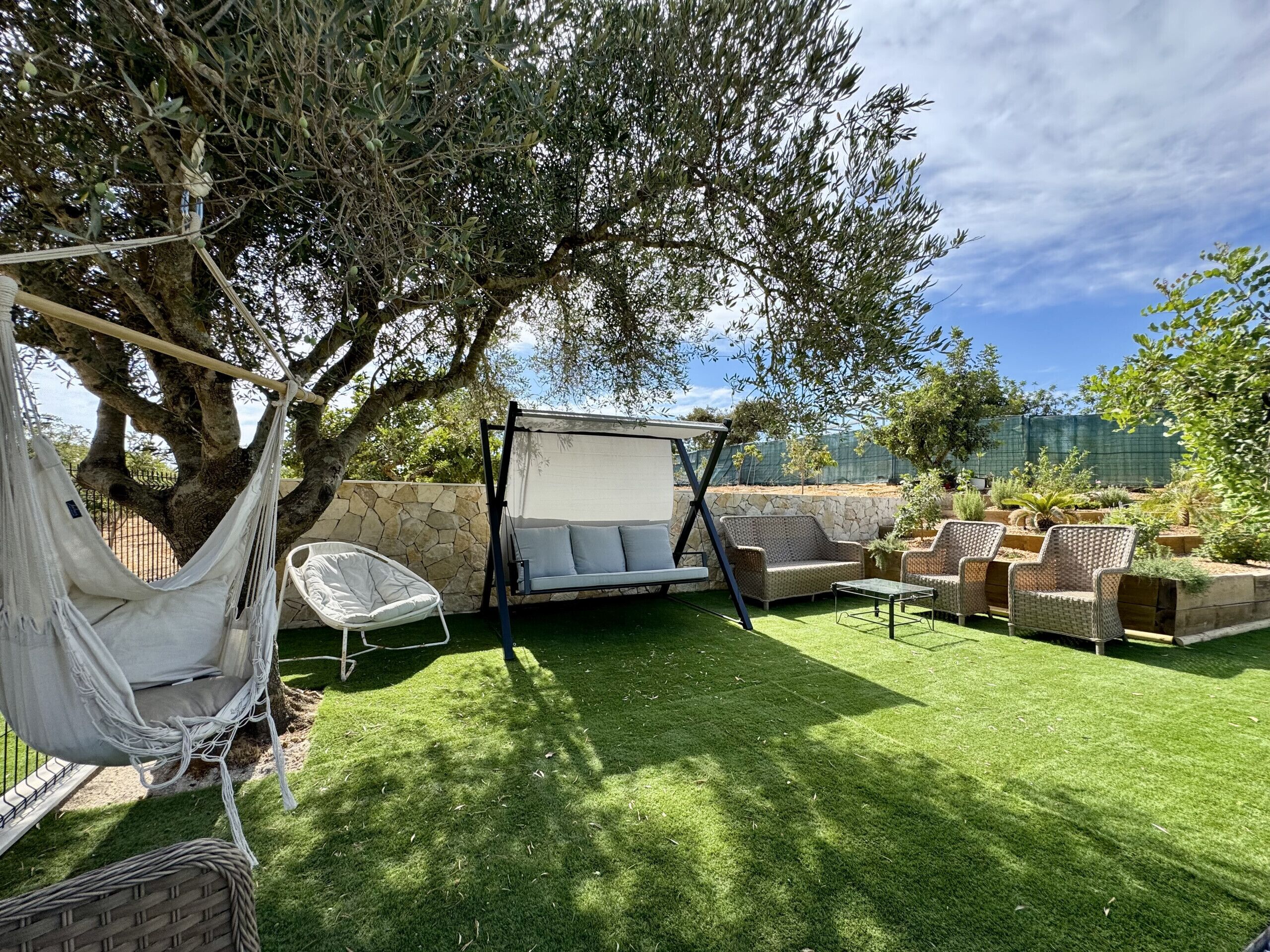 A backyard with a hammock, a swing, and outdoor furniture.