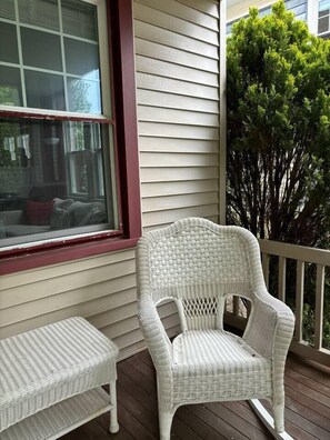 A wicker chair and bench on a wooden deck with a window and a tree in the background. - • Family Beach Condo • Walk to Beach • Porch (Ocean City)