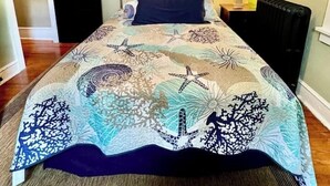 Una camera da letto con un letto, un comodino, una lampada, un quadro appeso al muro e una porta.