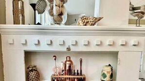 Uno scaffale bianco con diversi oggetti decorativi, tra cui un'ananas, un contenitore a forma di ananas e una bottiglia verde.